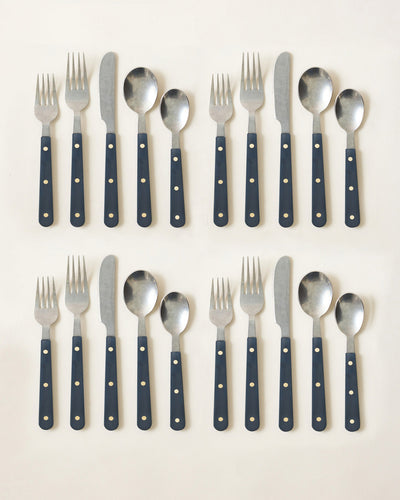 Two complete navy-handled cutlery settings with polished stainless-steel heads and contrasting brass-toned rivets.