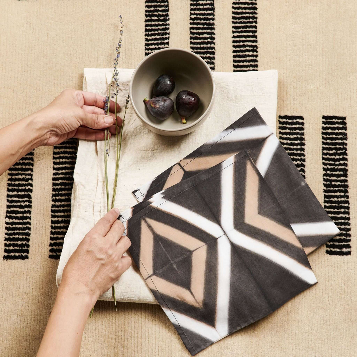 Woman wearing the oversized neutral beige Forest Night scarf, showing its dark woven flecks and softly fringed edges.