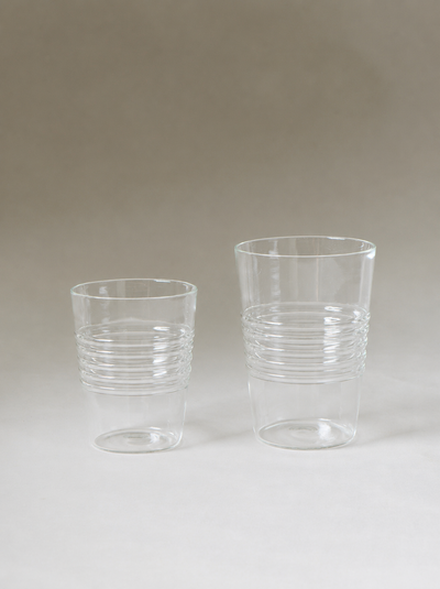 Two empty clear tumblers in different sizes, each detailed with horizontal ridges around the lower half.