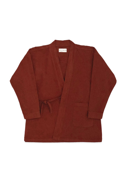 Front product view of the rust-red GI wrap jacket with waist ties and patch pockets.