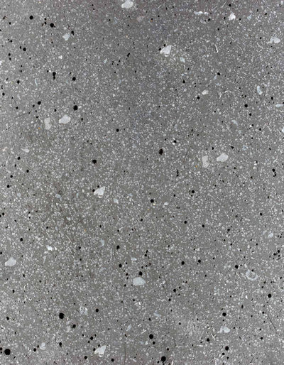 Close-up of the graphite finish on the Tortuga Forma Platform Planter Small - Terrazzo, showing irregular white, light grey and black chips embedded in a grey background.