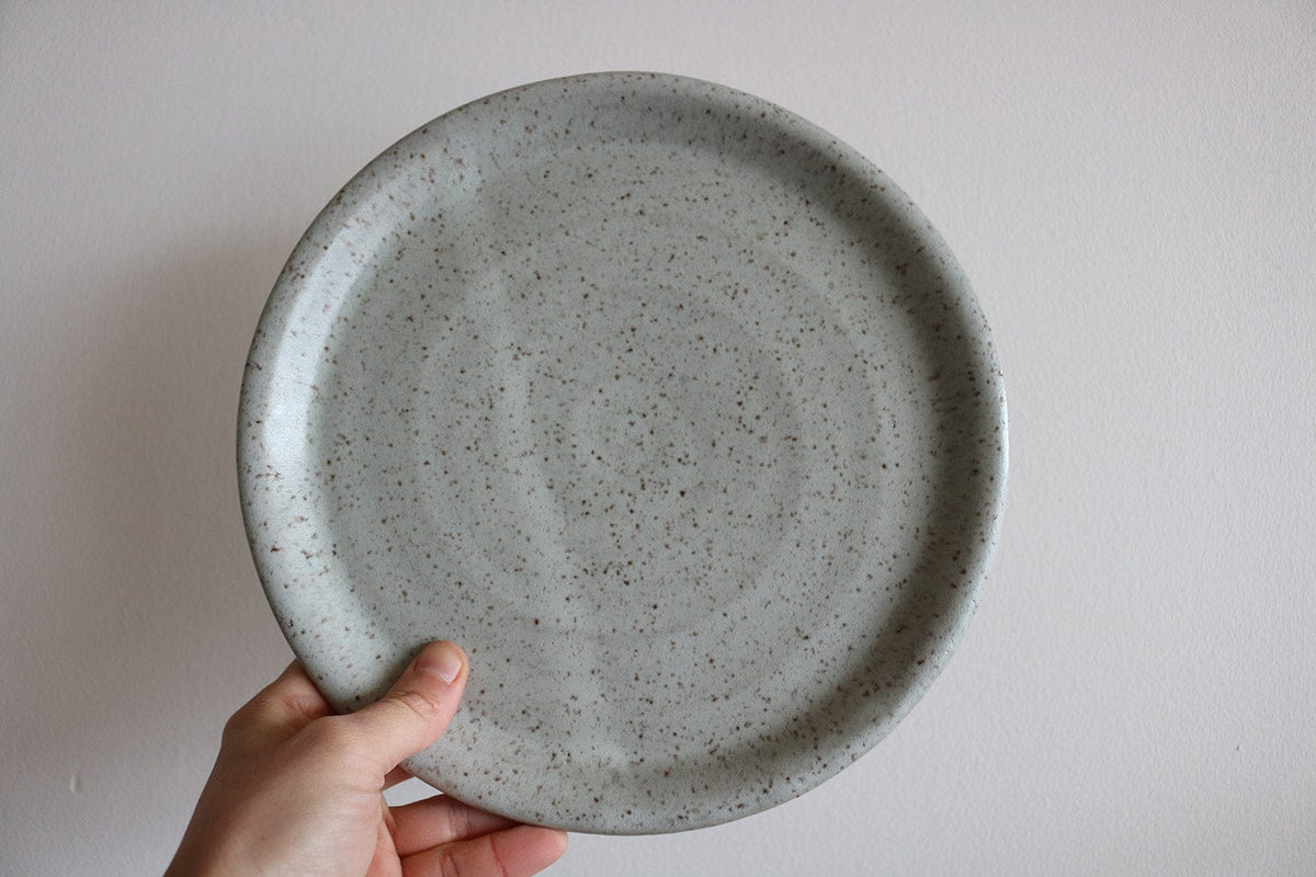 Gray speckled handmade ceramic dinner plate held in hand