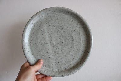 Gray speckled handmade ceramic dinner plate held in hand
