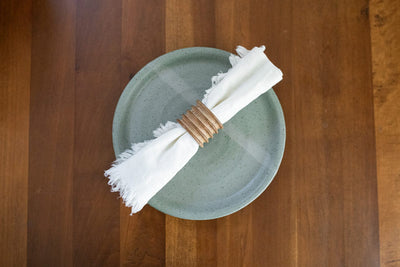 Handmade green earthenware dinner plate with folded napkin on wood table