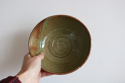 Handmade green glazed ceramic cereal bowl held in hand