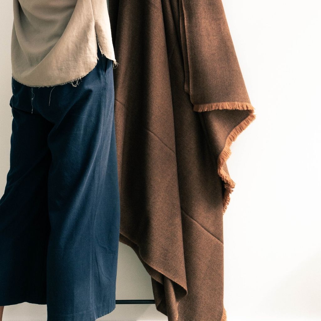 Person holding the Hay Brown handwoven throw open to display its generous size, warm brown color and short fringe