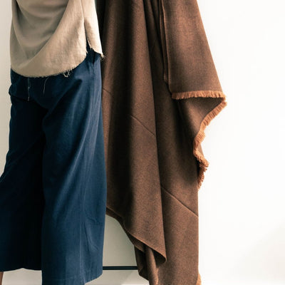 Person holding the Hay Brown handwoven throw open to display its generous size, warm brown color and short fringe