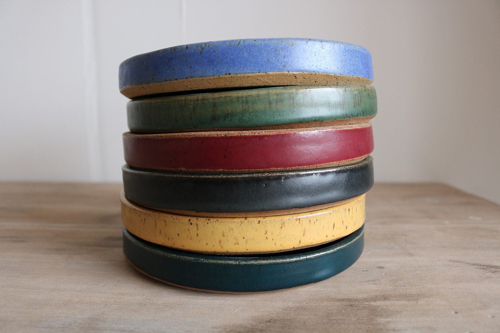 Stack of handmade small plates in assorted glaze colors