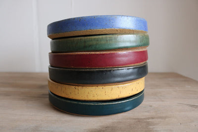 Stack of handmade small plates in assorted glaze colors