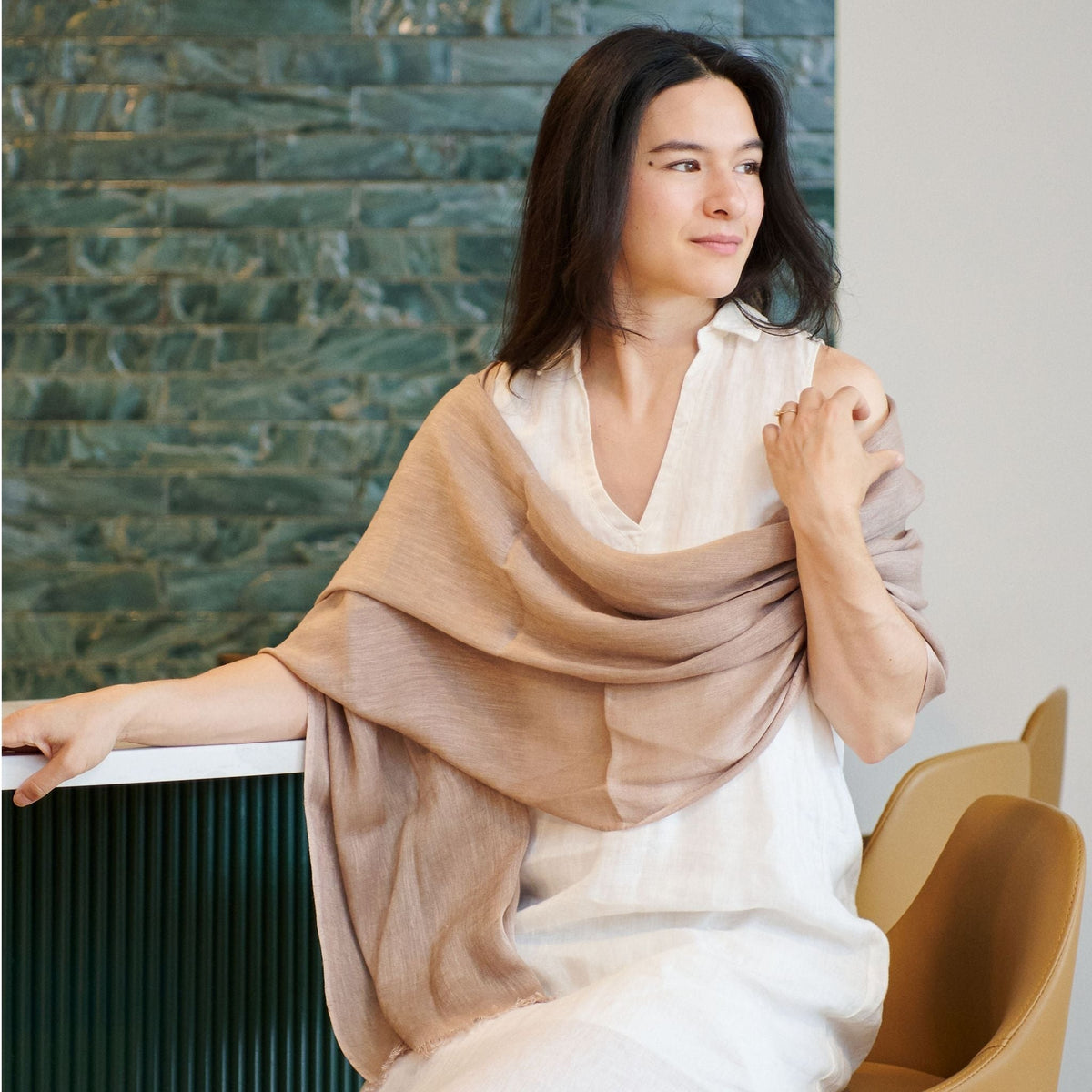 Close lifestyle view of the Jute Golden Brown handwoven scarf wrapped in soft layers over a white dress