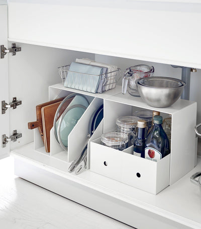 Kitchen cabinet with organized storage shelves holding various kitchen items. Riser (Set of 2) - Steel