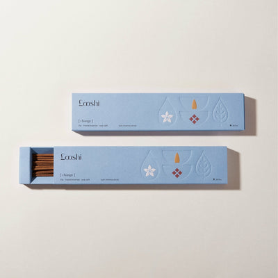 Open and closed light blue boxes of Looshi Change incense sticks displayed on a cream background