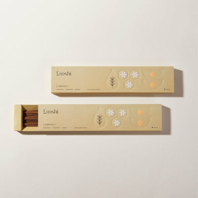 Open and closed golden yellow boxes of Looshi Euphoria incense sticks with floral and botanical designs on a cream background