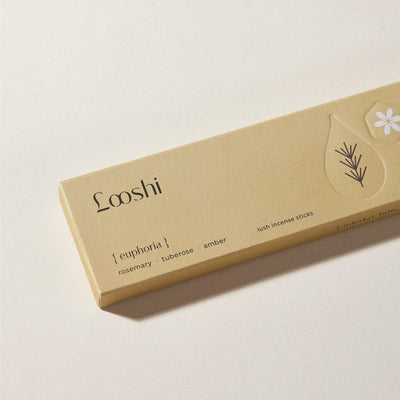 Golden yellow box of Looshi Euphoria incense sticks on a cream surface, featuring rosemary, tuberose and amber fragrances