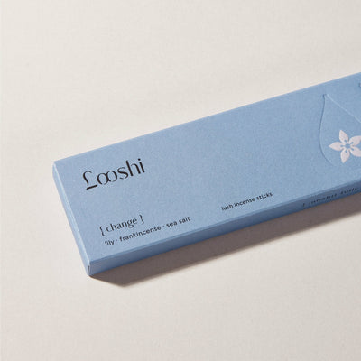Light blue box of Looshi Change incense sticks on a cream surface, featuring lily, frankincense and sea salt fragrances