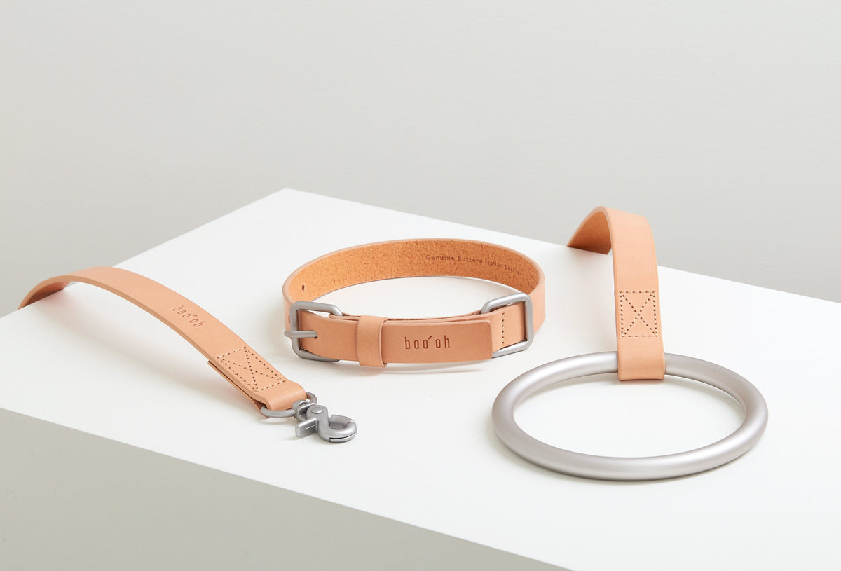 Peach Lumi Leash arranged with its coiled strap, silver clasp, short connector loop, and large round handle on a white display block.