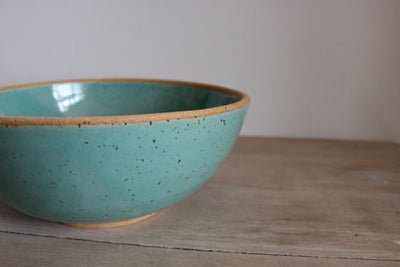 Light teal handmade ceramic cereal bowl on wooden surface
