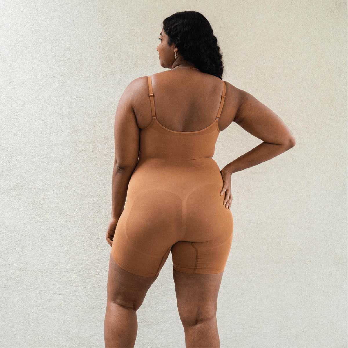 Back view of model wearing PROCLAIM Mid-Thigh Shapewear Bodysuit in Maya Nude