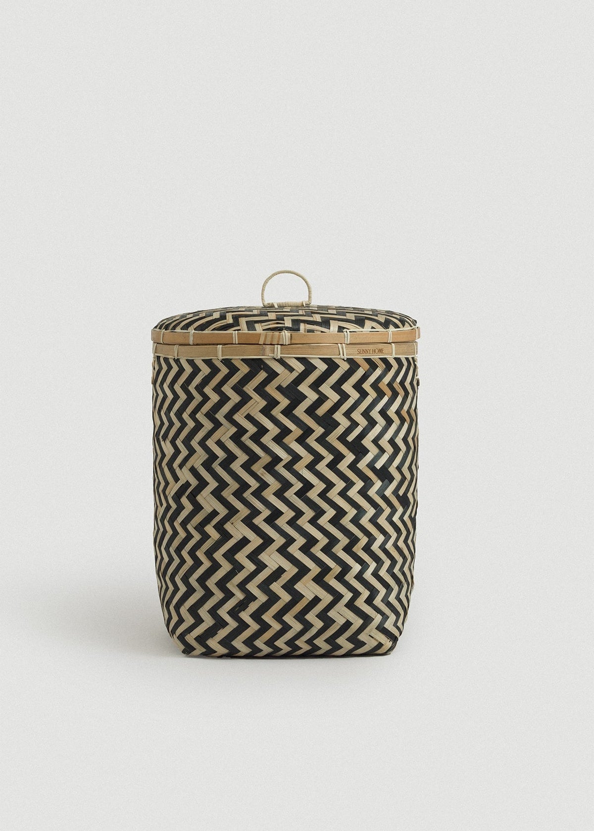 Medium cylindrical bamboo basket with a fitted lid, loop handle, and black-and-natural zigzag weave.