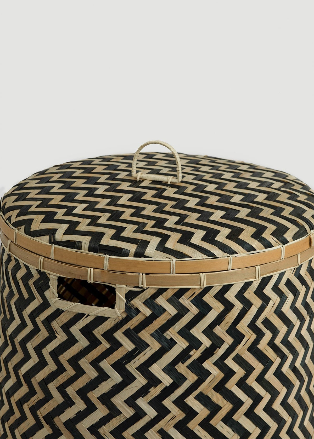 Close-up of the chevron-woven lid, loop handle, reinforced bamboo rim, and side opening.