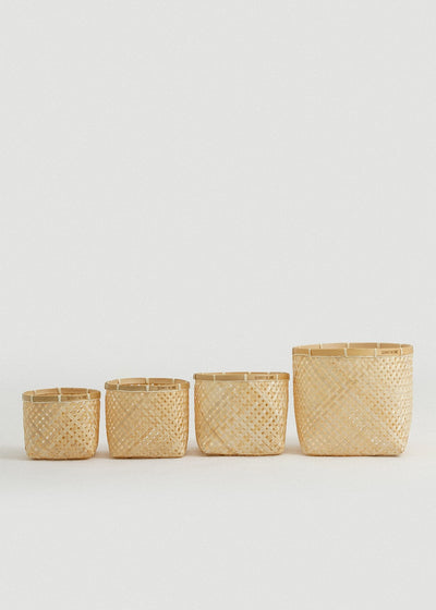 Set of four natural woven bamboo organizing baskets arranged from smallest to largest.