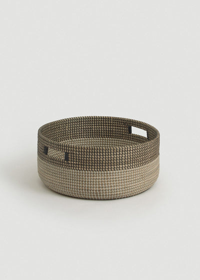 Low round seagrass floor basket with a natural base, black upper band, and two rectangular cutout handles.