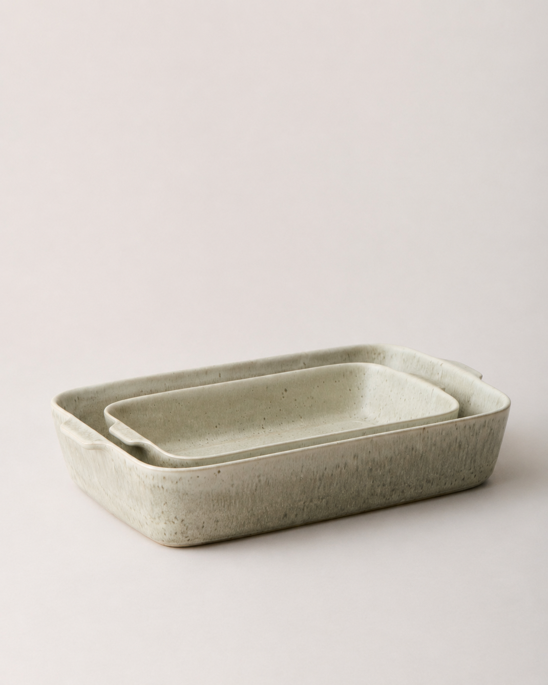 Two warm stone Fieldstone Bakers nested together, with mottled beige-gray glaze and small handles visible at both ends.