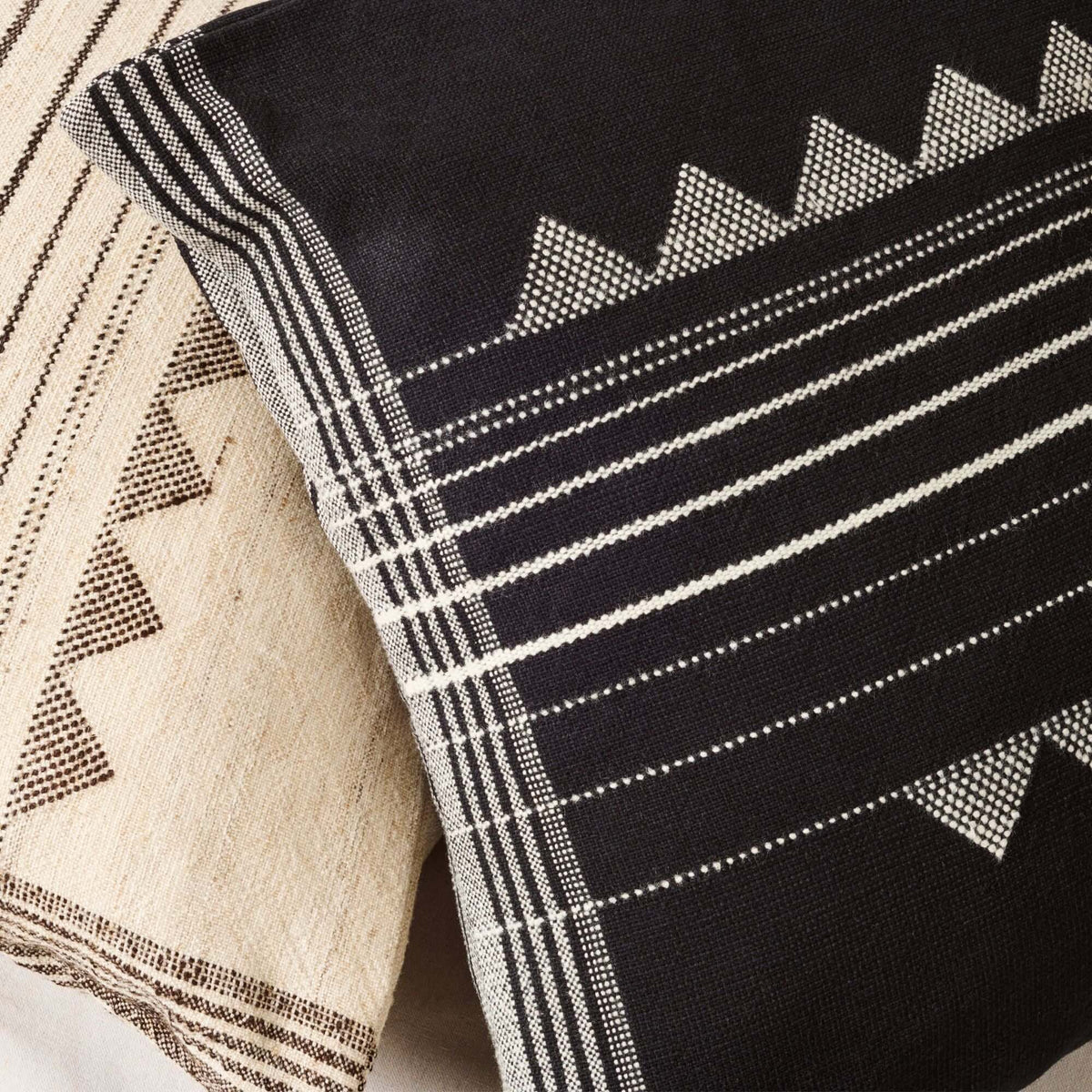 Close-up of the Kora Black pillow’s woven geometric pattern beside a coordinating ivory pillow cover