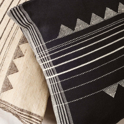 Close-up of the Kora Black pillow’s woven geometric pattern beside a coordinating ivory pillow cover