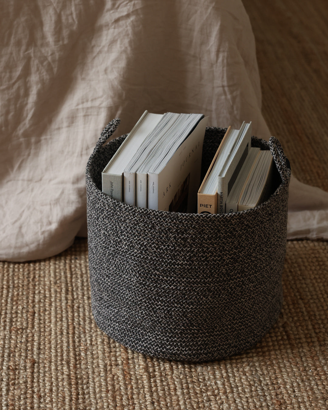 Small Gray Melange Loops basket used to store books beside a bed.