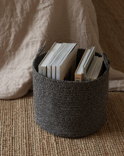 Small Gray Melange Loops basket used to store books beside a bed.