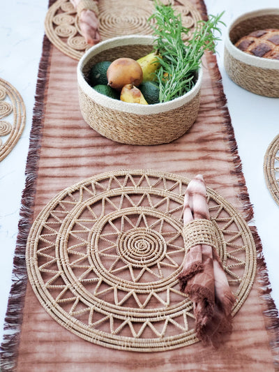 Korissa Woven Palm Fiber Napkin Ring styled with woven placemat on rust dip-dye table runner
