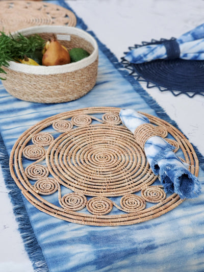 Korissa Woven Palm Fiber Napkin Ring styled with woven placemat on blue tie-dye table runner