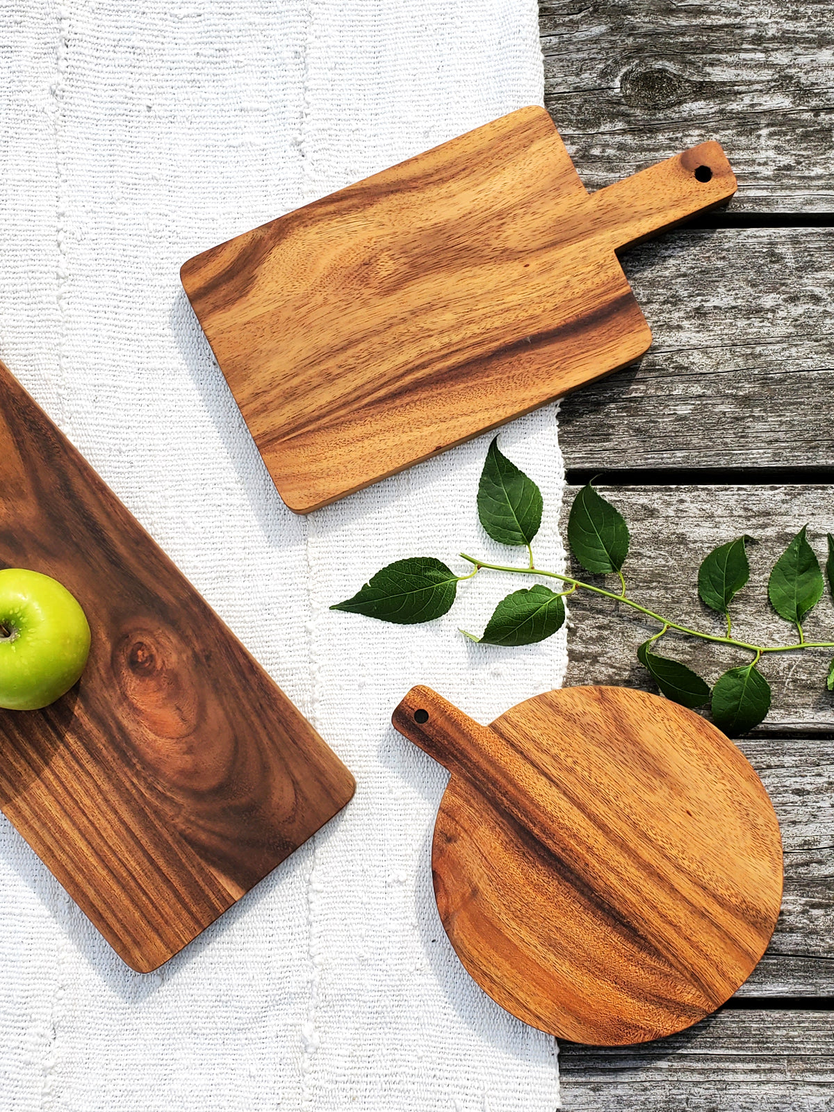 Korissa Wooden Serving Board beside round board, apple and greenery