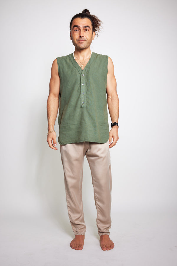 Man standing barefoot in blush Souk cupro silk pants with a sleeveless olive shirt.