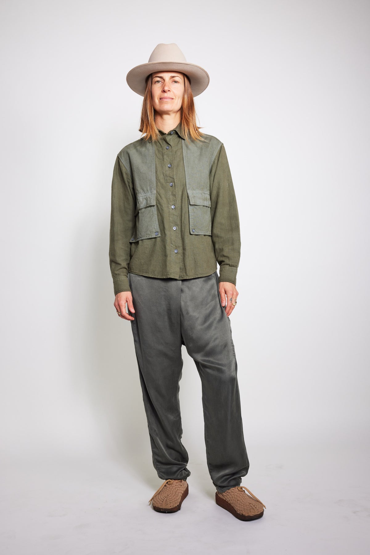 Front view of model wearing charcoal Souk pants with an olive jacket and beige hat.
