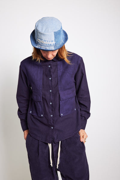 Model looking down in a navy Trek Shirt, matching drawstring pants, and a pale blue bucket hat.