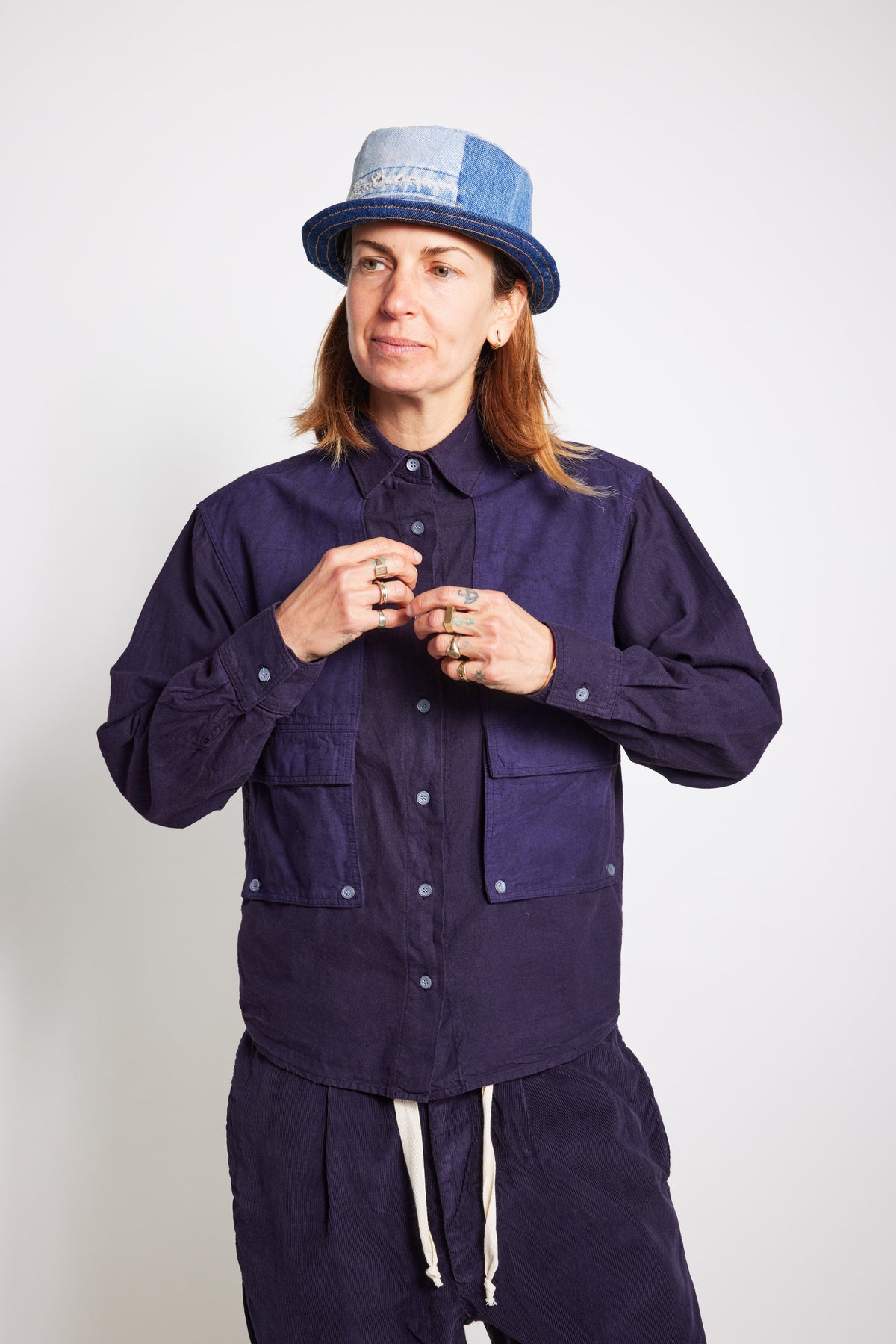 Close front view of a model adjusting the navy Trek Shirt, showing its button closure and utility pockets.