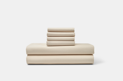 Stacked American Blossom Linens cotton percale sheet set in a natural neutral color