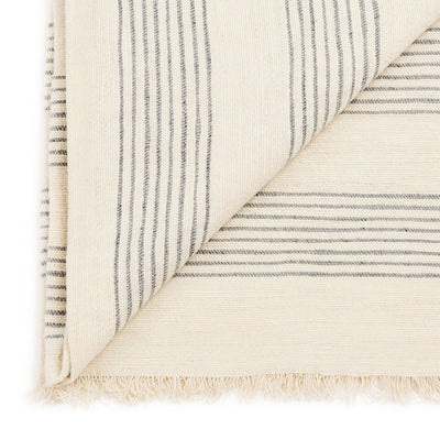 Close-up of the Silica Chalk throw’s folded corner, fine gray stripes and soft cream fringe