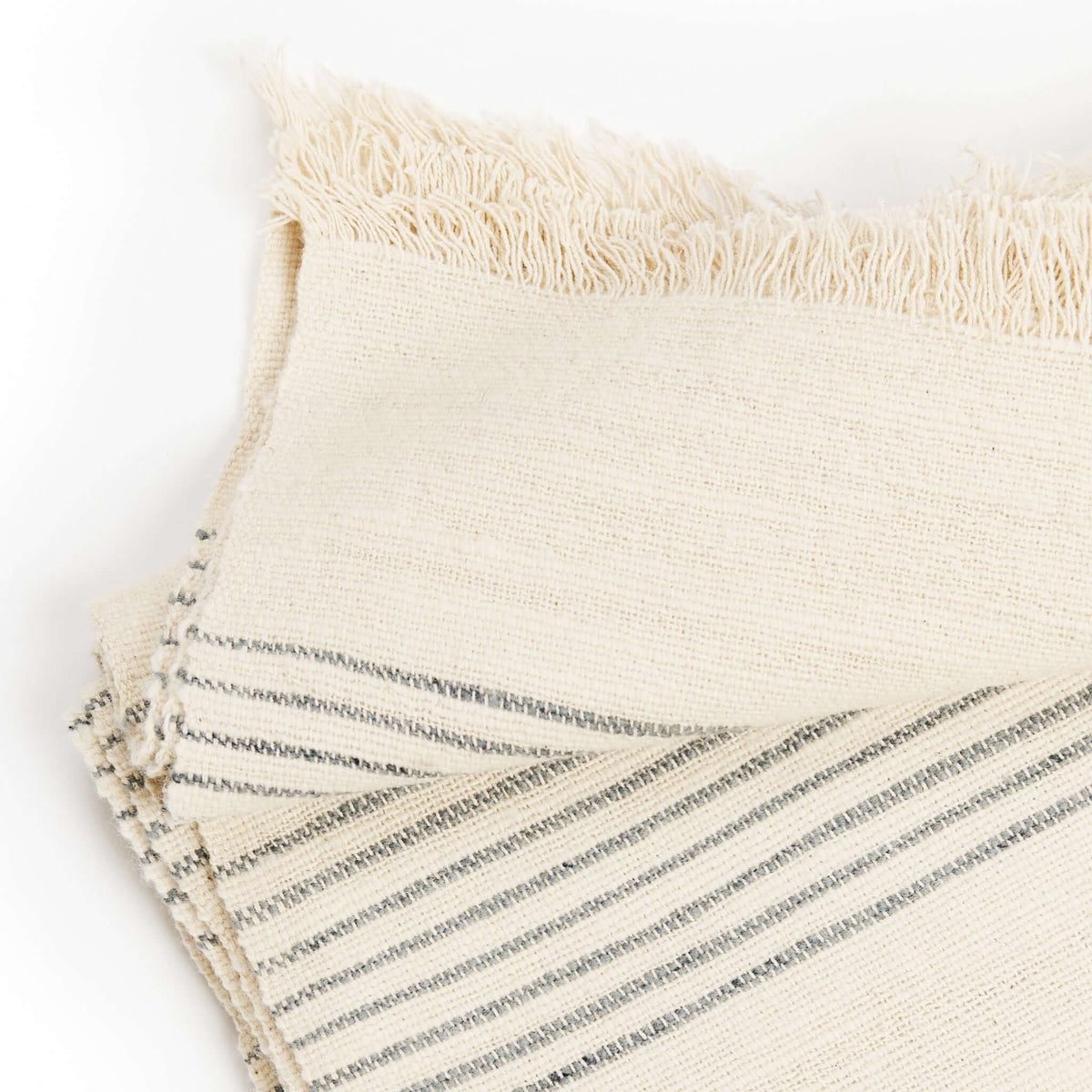 Detailed view of the Silica Chalk handwoven throw showing intersecting stripe directions and loosely textured fringe