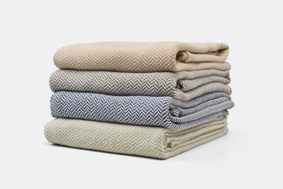 Stack of folded blankets in various patterns and colors on a white background