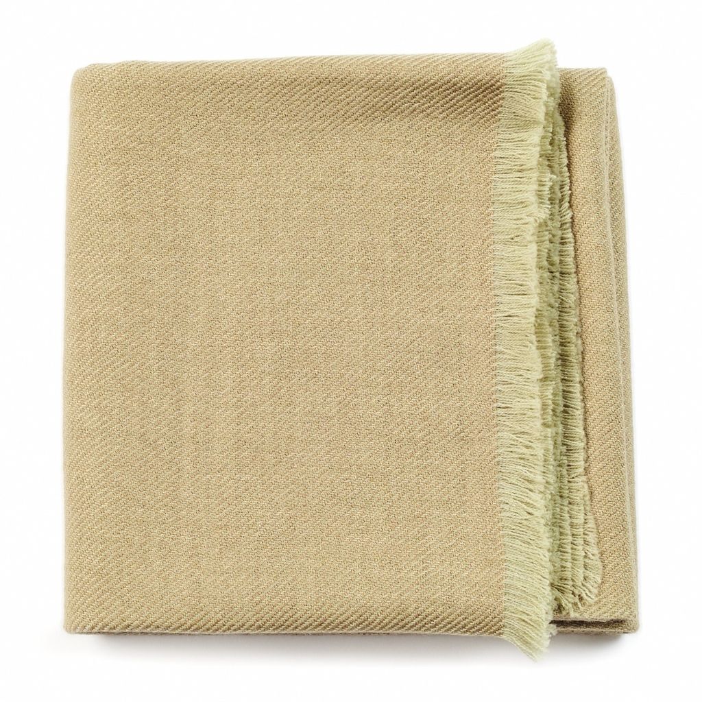 Folded pale sage-green color variation of the Variously merino throw with a muted green fringed edge