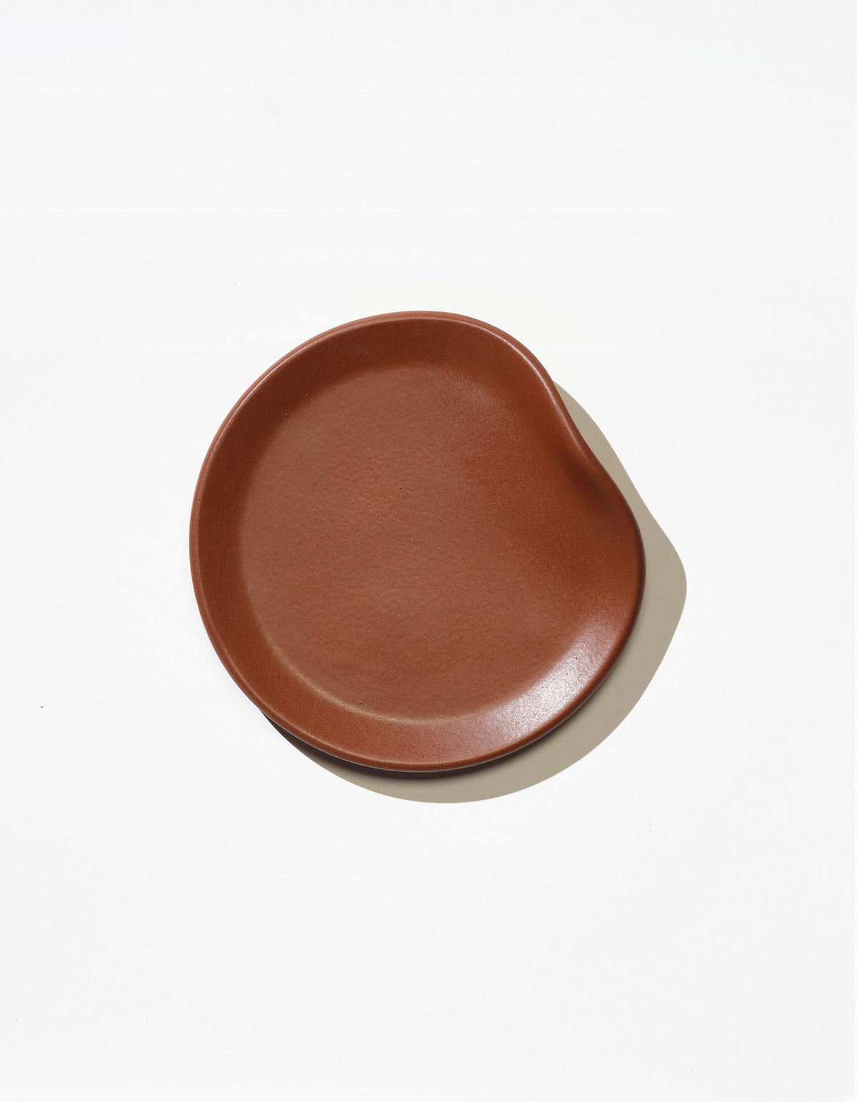 Tortuga Forma Bread Plate Single in Tierra viewed overhead on white, showing its glazed finish, subtly textured centre and gently asymmetrical raised rim.