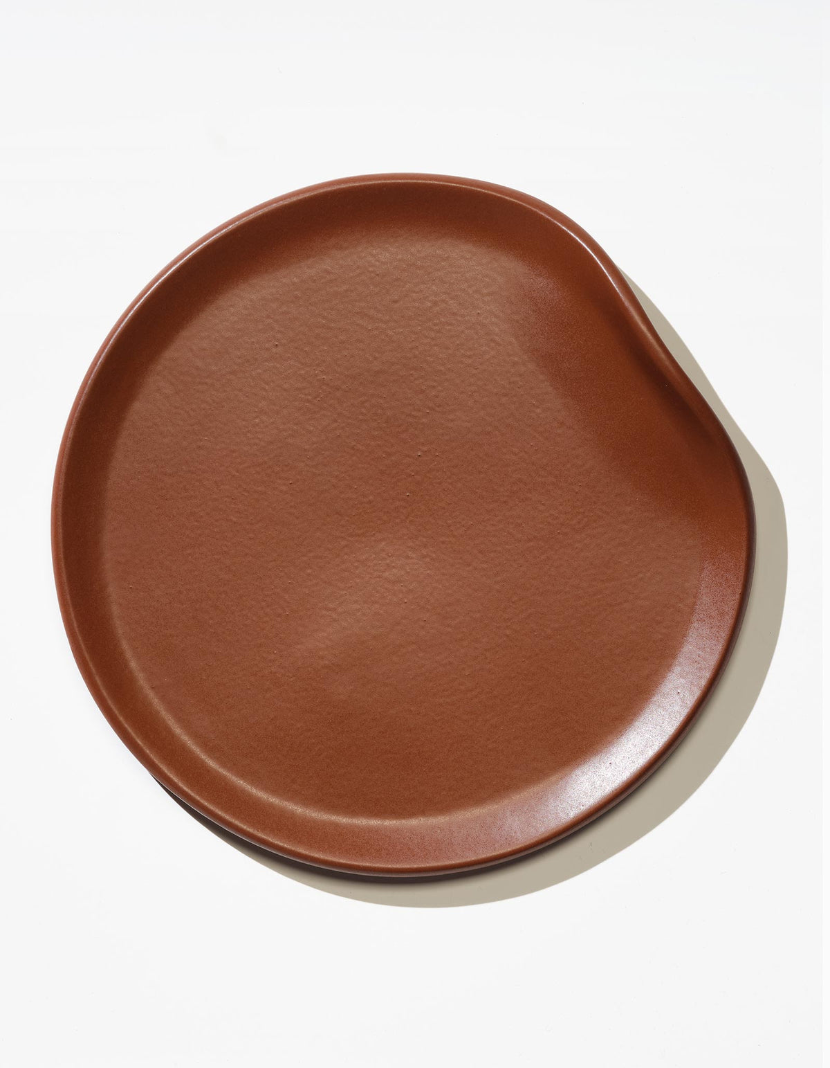Tortuga Forma Dinner Plate Single in Tierra viewed overhead on white, showing its glazed finish, subtly textured centre and gently uneven raised rim.
