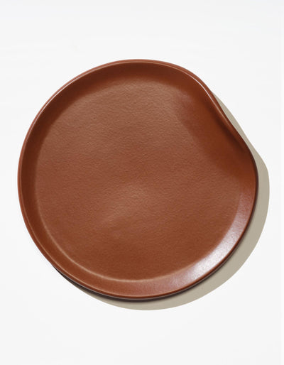Tortuga Forma Dinner Plate Single in Tierra viewed overhead on white, showing its glazed finish, subtly textured centre and gently uneven raised rim.