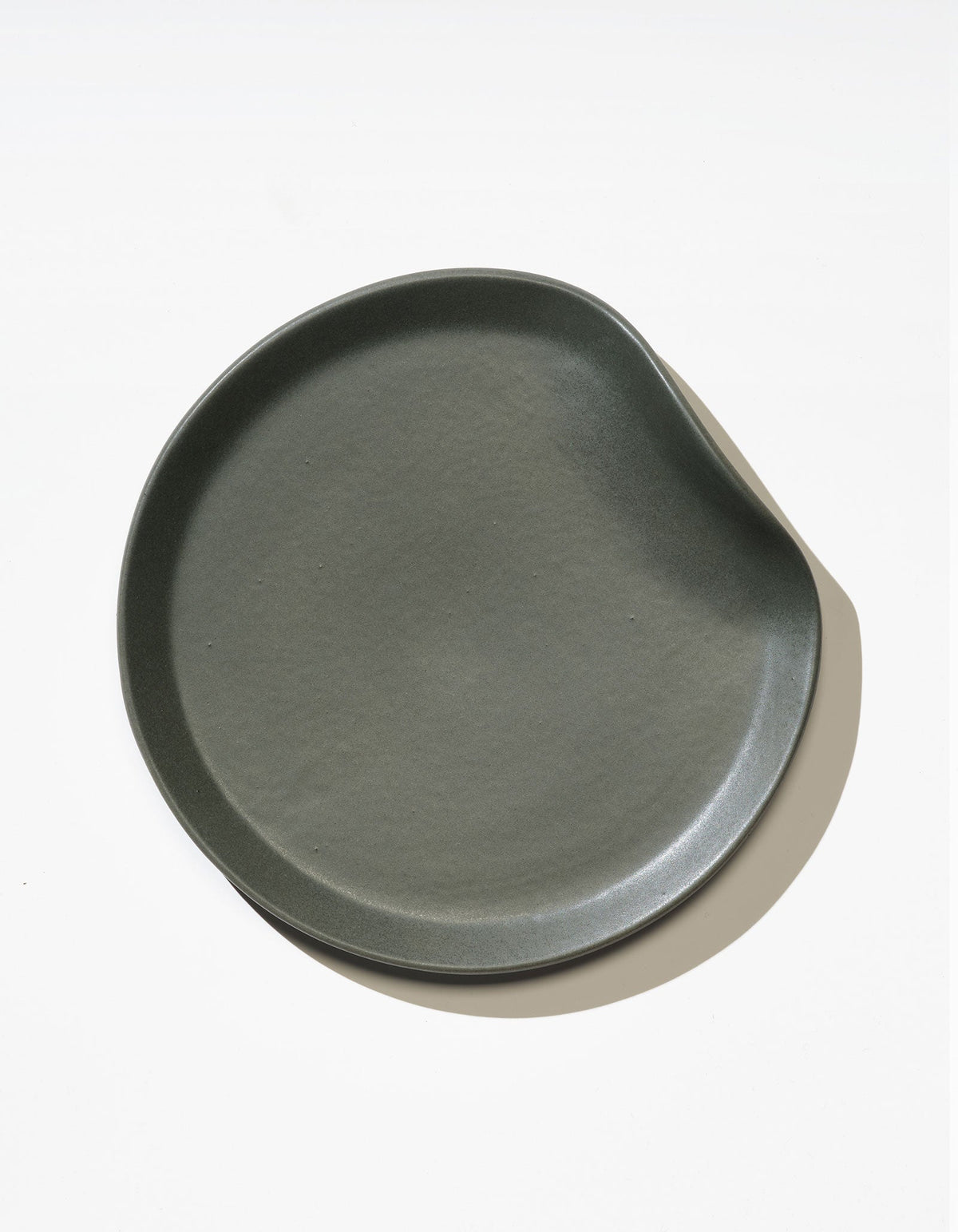 Tortuga Forma Salad Plate Single in Liche viewed overhead on white, showing its asymmetrical outline, curved raised rim and finely textured centre.