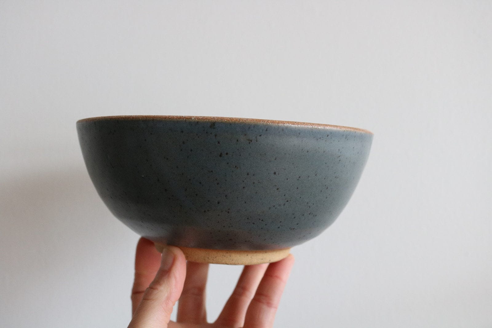 Teal handmade ceramic cereal bowl held in hand
