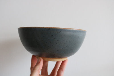 Teal handmade ceramic cereal bowl held in hand