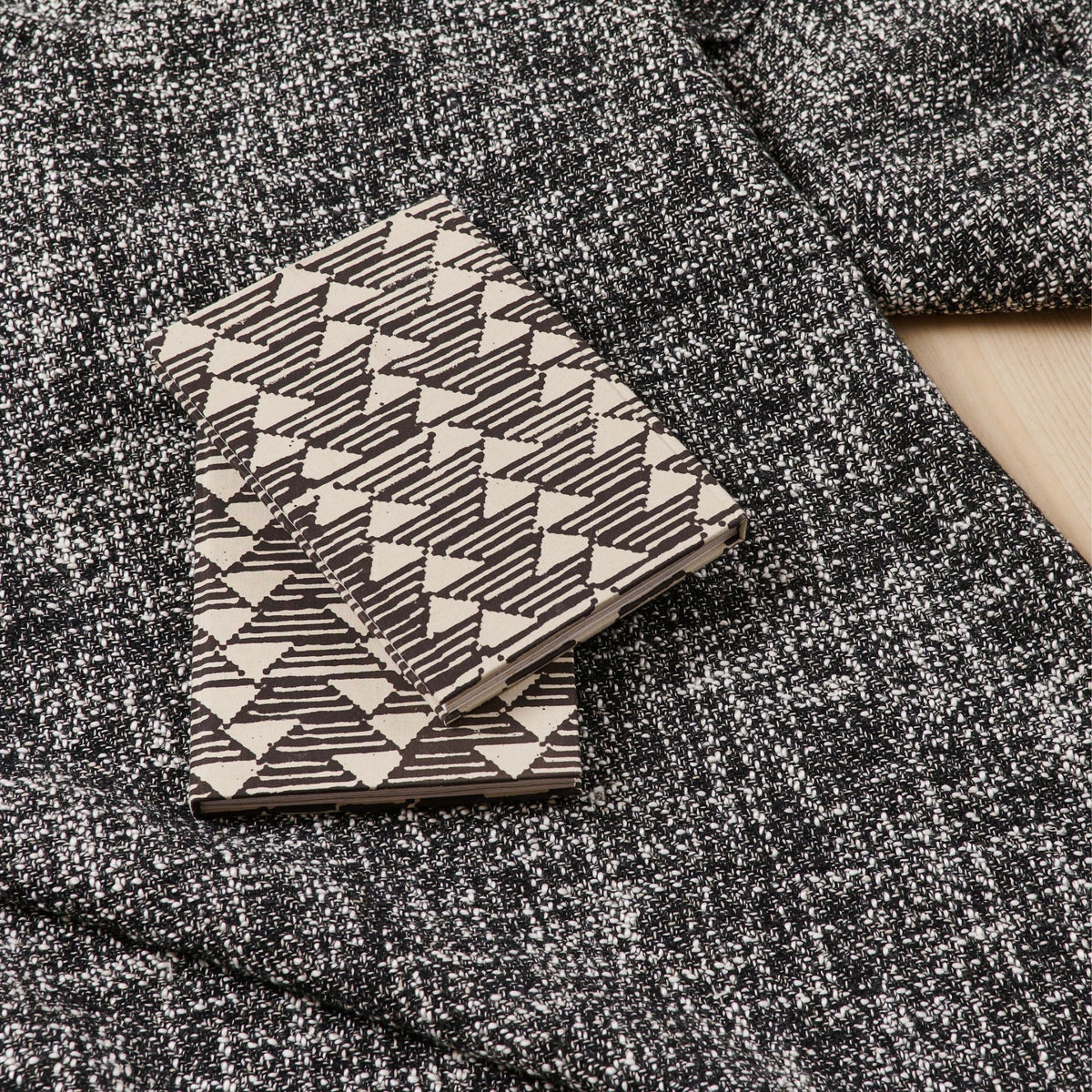 Tria Black White handmade journal resting on a textured charcoal-gray blanket